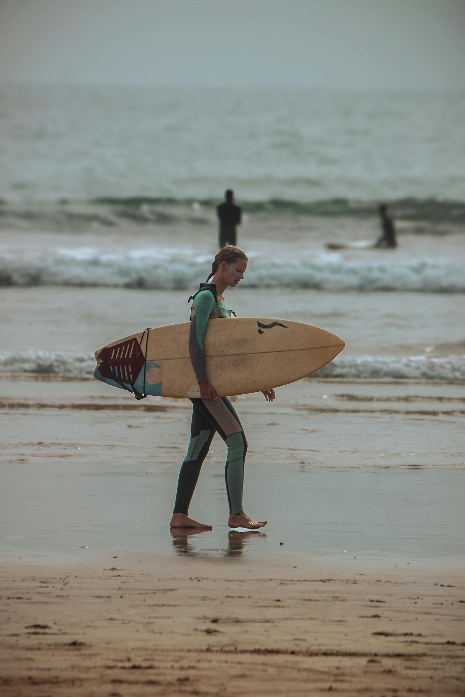 Surfer walking down the beach at Tamraght near Agadir, Morocco