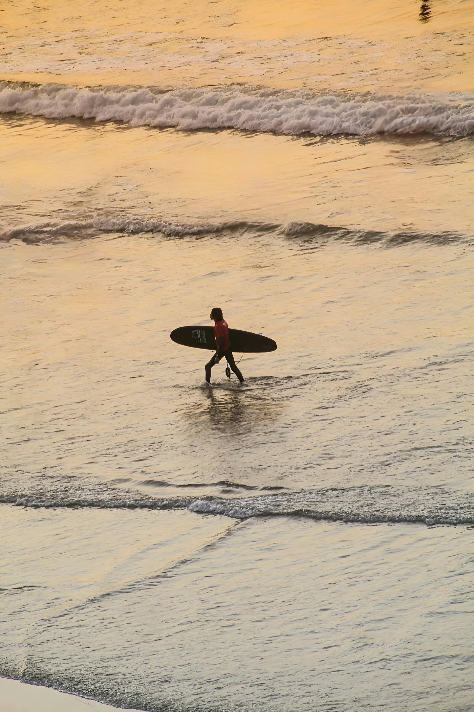 Solo Moroccan surfer silhouetted at sunset on the Agadir coast