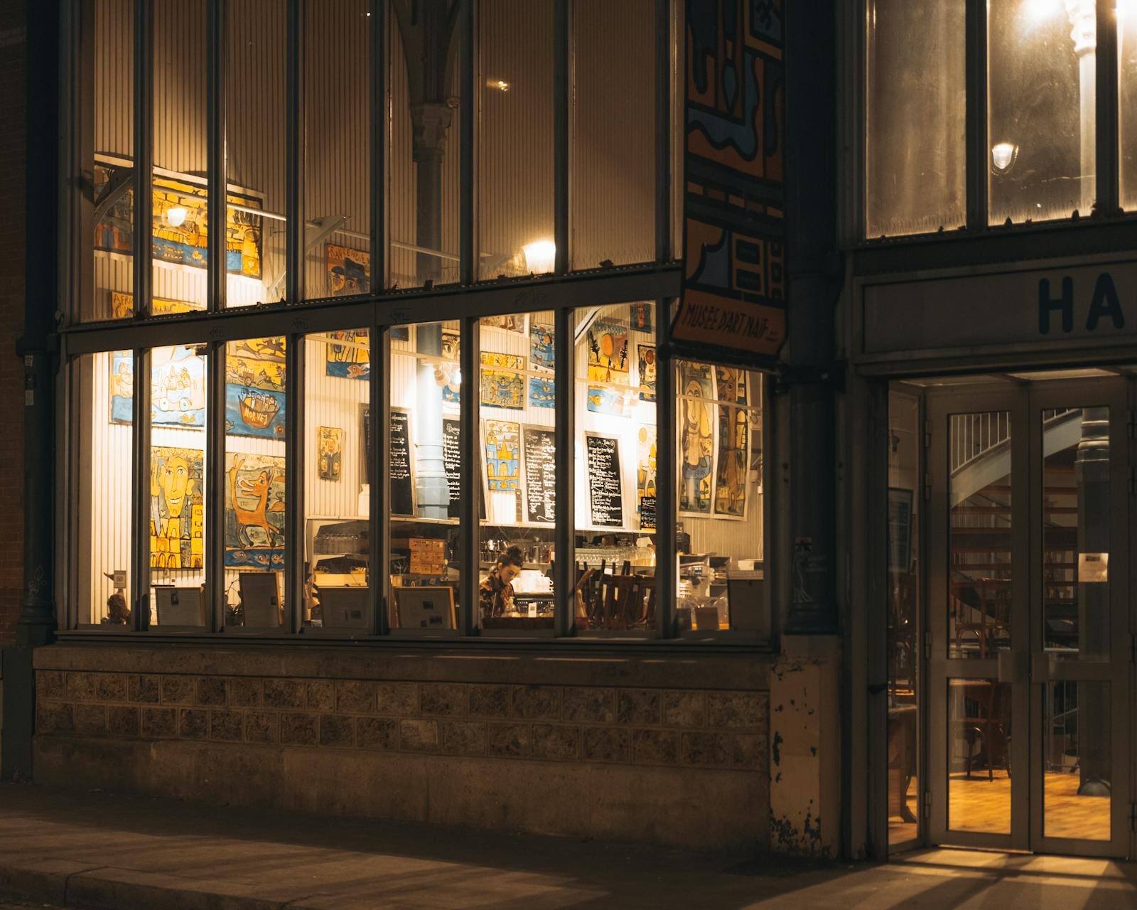 Restaurant exterior at dusk with warm windows and palm tree, Agadir