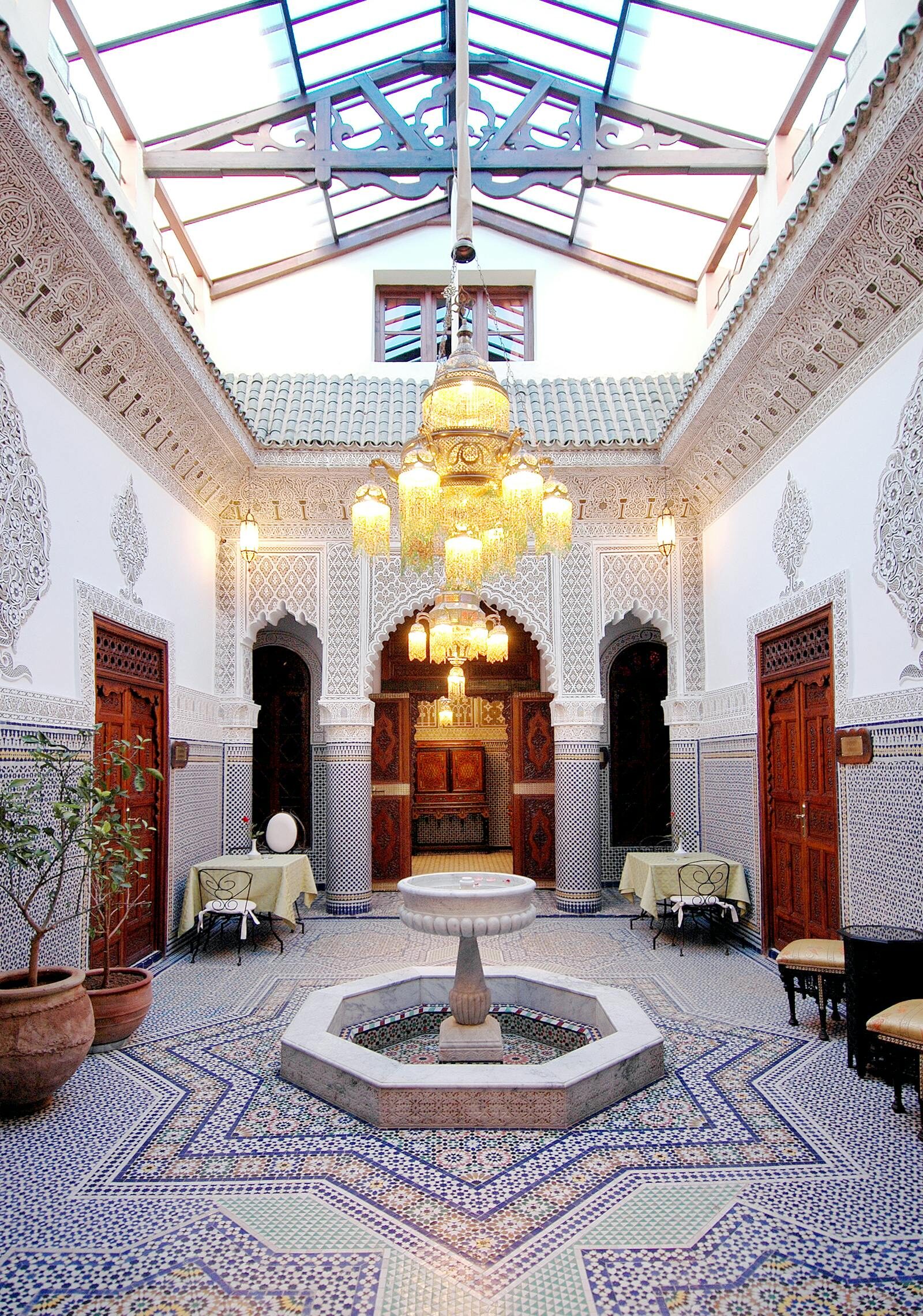 Moroccan restaurant interior with zellige tiles, lanterns and low banquettes