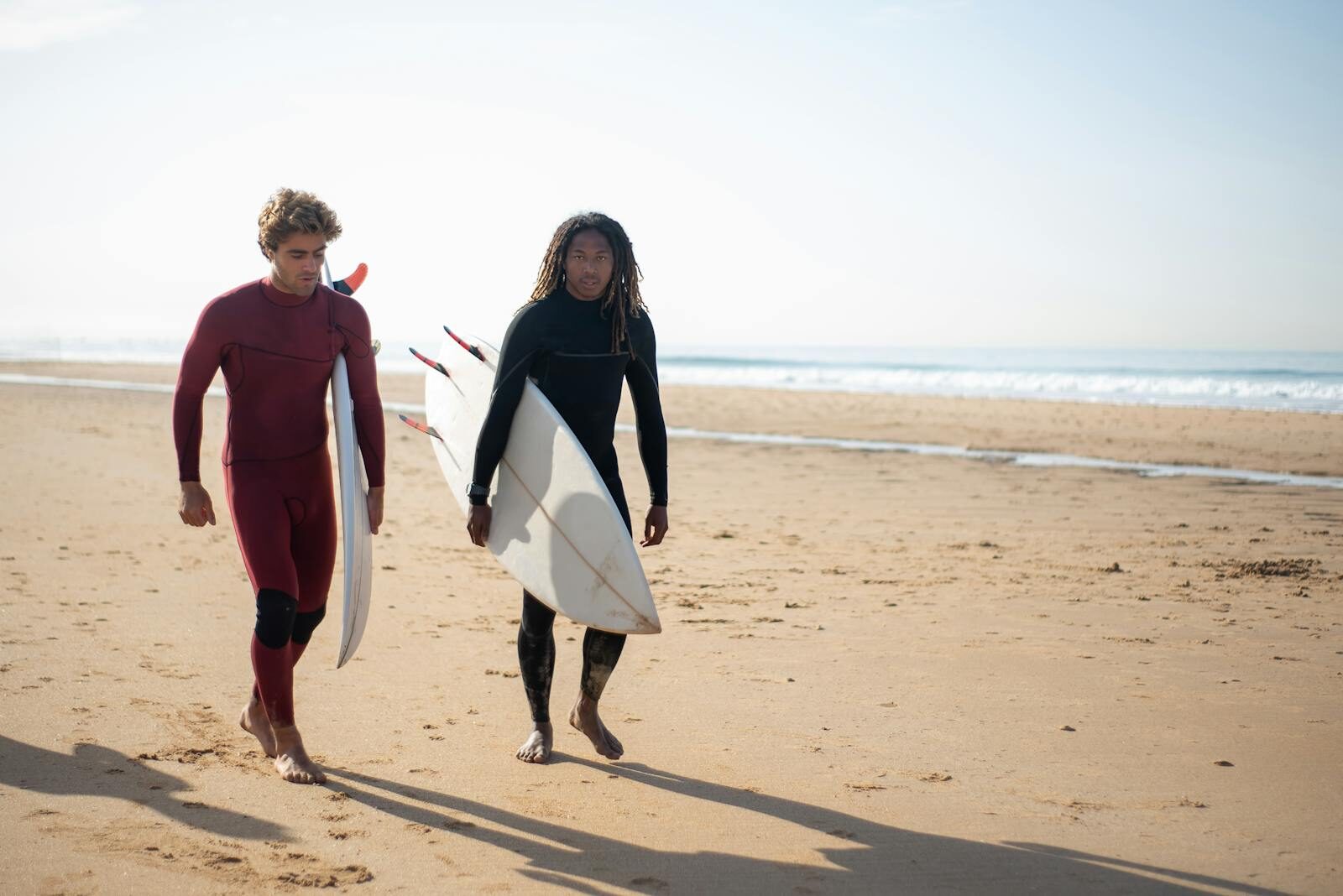 Surfer walking up the beach with board after the morning session