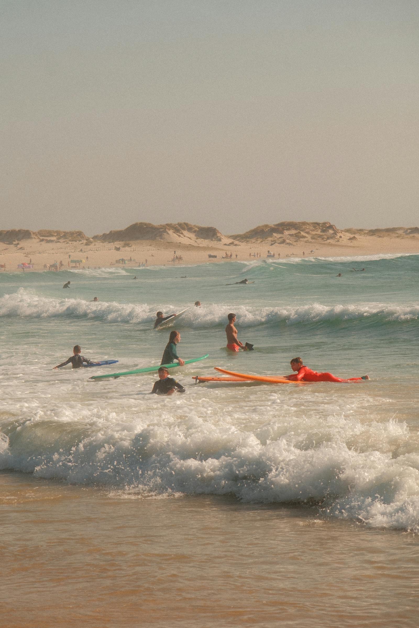 Uncrowded lineup with a handful of surfers in warm light, the in-between season