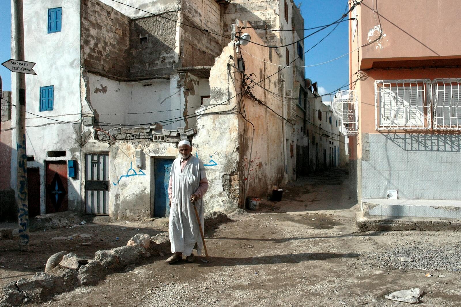 Whitewashed narrow alley in a Moroccan coastal village with elderly resident walking